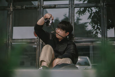 Full length of man photographing while sitting in mirror