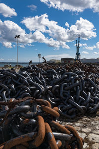 Stack of firewood on beach against sky