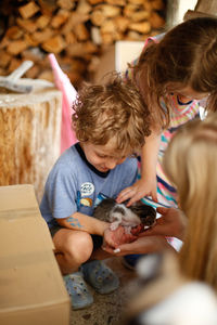 Two happy children petting a tiny kitten outside