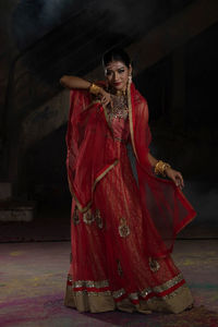 Full length of young woman standing against black background