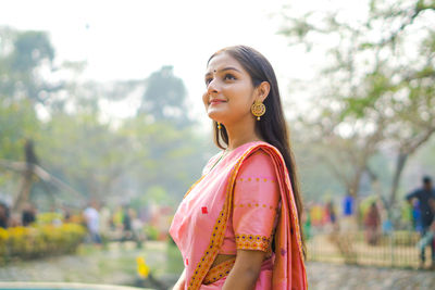 Smiling young woman standing against blurred background