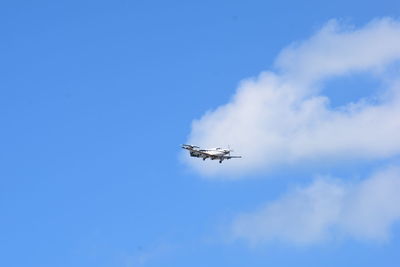 Low angle view of airplane flying against blue sky