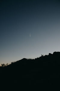 Silhouette landscape against clear sky at night