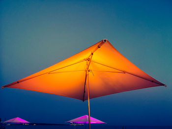 Illuminated umbrella on beach at dusk