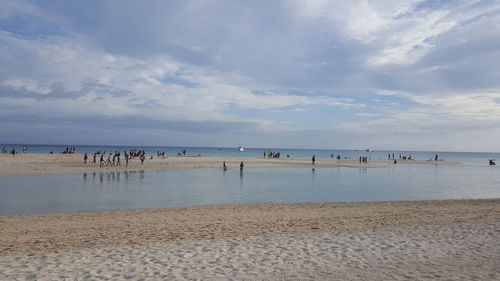 Group of people on beach against sky