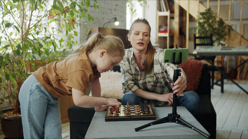 Mother and daughter playing chess while vlogging