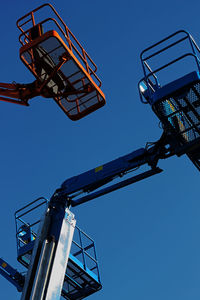 Low angle view of crane against clear blue sky