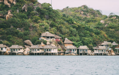 Houses by lake and buildings against sky