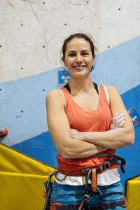 Portrait of smiling woman against climbing wall