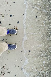 Low section of man standing on sand at beach