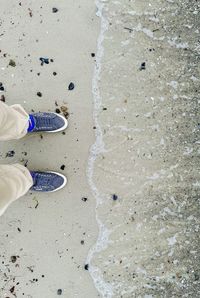 Low section of man standing on sand at beach