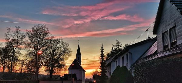 Silhouette trees and buildings against sky during sunset