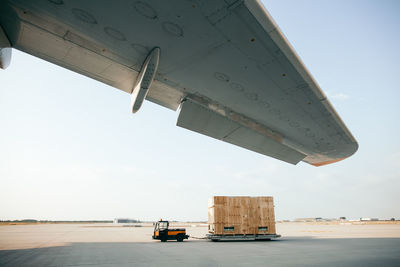 Cropped image of airplane at runway against clear sky during sunny day