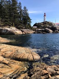 Scenic view of rocks and lighthouse by the sea against sky