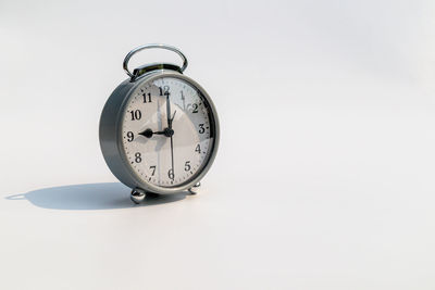 Close-up of clock on table against white background