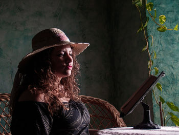 Woman reading book while sitting by table at home