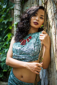 Close-up of smiling young woman standing against tree