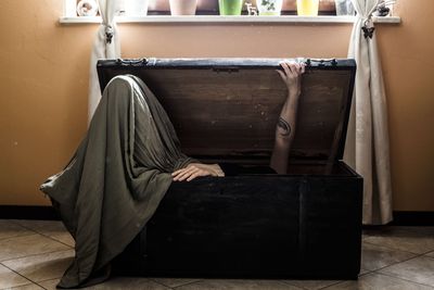 Young woman closing herself in container at home