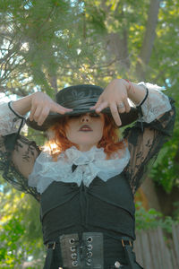 Young woman wearing hat standing against trees