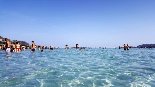 People in swimming pool against clear sky