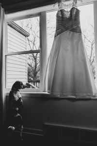 Rear view of woman looking through window at home
