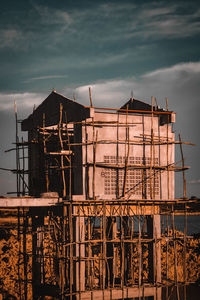 Exterior of old building by construction against sky