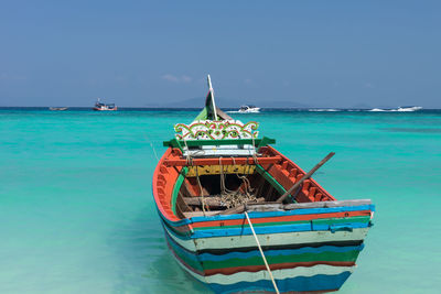 Boat moored in sea against blue sky