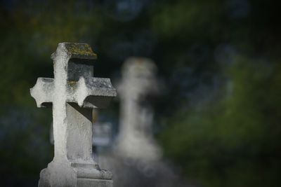 Close-up of cross in cemetery against sky