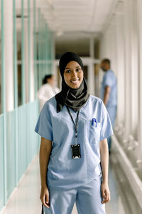 Portrait of smiling female nurse standing in hospital corridor