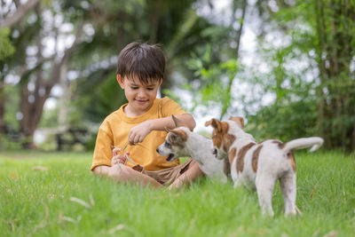 Full length of boy with dog on grass