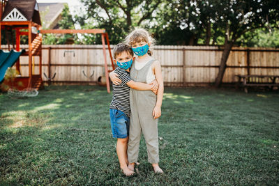 Two young kids hugging outside while wearing homemade fabric masks