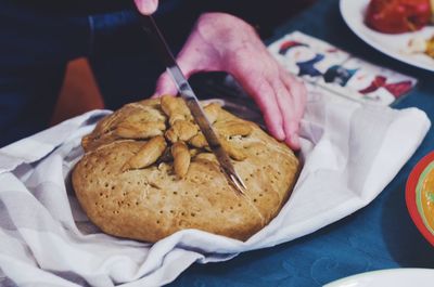 Cropped image of person cutting sweet bread at table