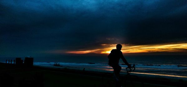 Silhouette of people on beach at sunset