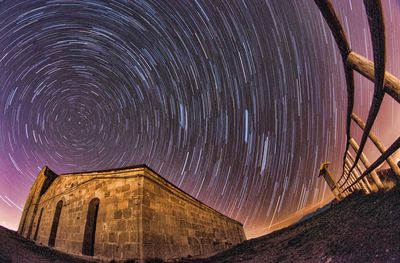 Low angle view of built structure against star trail