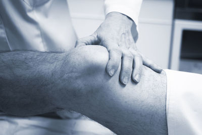 Close-up of doctor examining patient knee in hospital