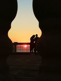 Silhouette people standing against orange sky