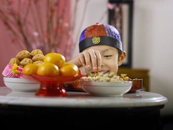 Close-up of boy picking food in container at table