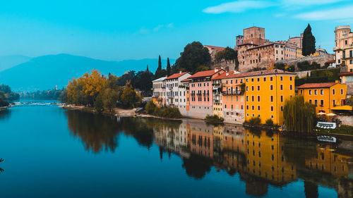 Scenic view of lake by buildings against blue sky