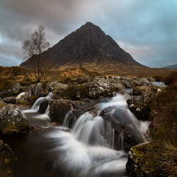 Scenic view of waterfall against cloudy sky