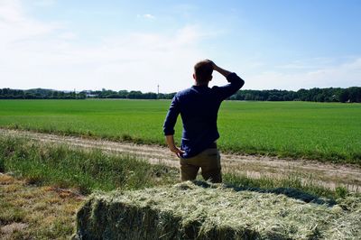 Rear view of man standing on field against sky