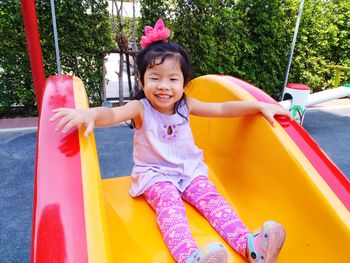 Cute smiling girl sitting on slide at playground