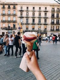 Cropped image of people holding ice cream in city