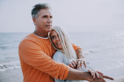 Smiling woman with boyfriend romancing at beach