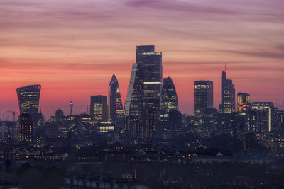 Illuminated buildings in city against sky during sunset