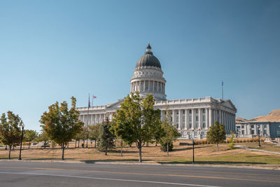 Empty road by state capitol building with clear blue sky in background in summer