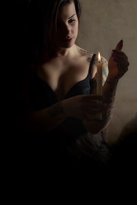 Midsection of woman holding cigarette against black background