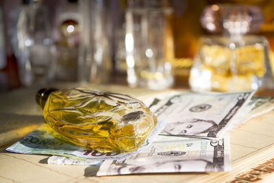 Close-up of perfume bottle and paper currency on table