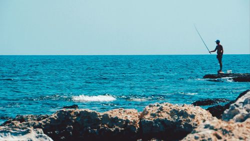 Man surfing in sea against clear sky