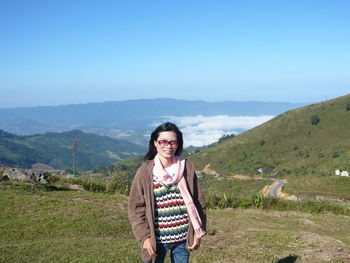 Portrait of smiling woman standing on mountain against sky