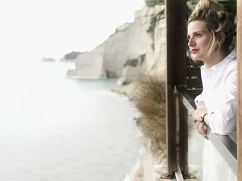 Side view of woman looking at sea against sky